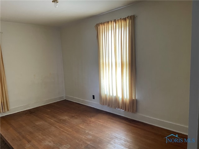 spare room featuring dark wood-type flooring and plenty of natural light