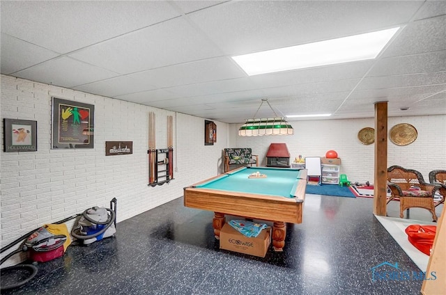 game room with a paneled ceiling, brick wall, and pool table