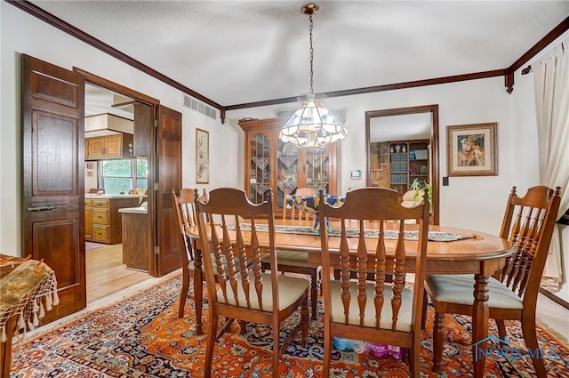 dining room with a textured ceiling, a notable chandelier, light hardwood / wood-style floors, and crown molding