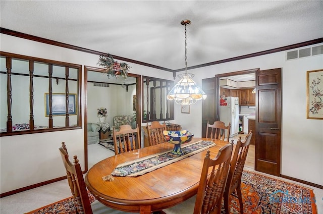 carpeted dining room with a textured ceiling, crown molding, and a chandelier