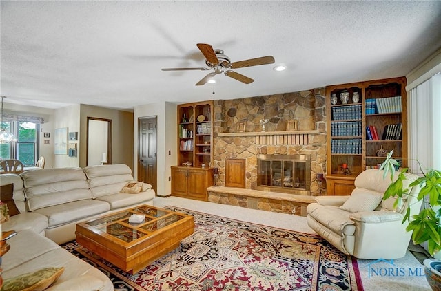 living room featuring a fireplace, a textured ceiling, built in features, and ceiling fan