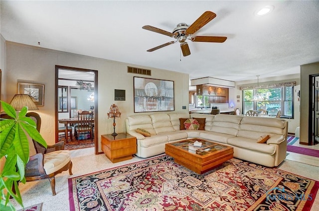 living room with ceiling fan and a textured ceiling