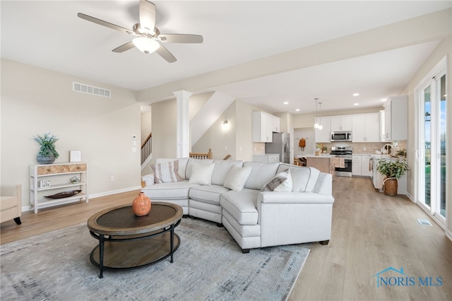 living room with a wealth of natural light, sink, ceiling fan, and light hardwood / wood-style floors