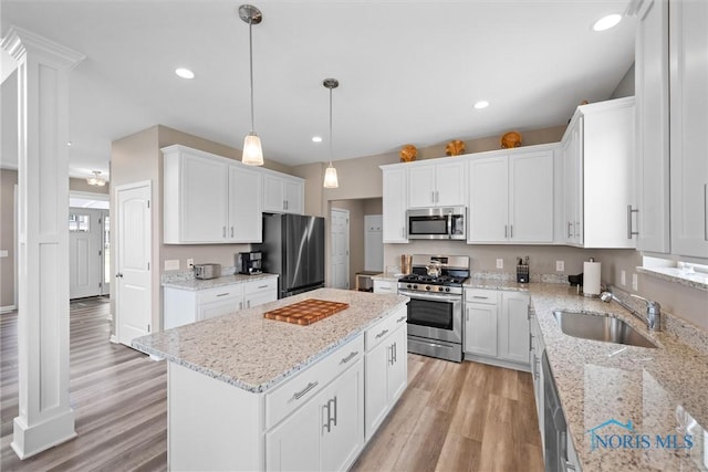 kitchen featuring sink, decorative light fixtures, a center island, appliances with stainless steel finishes, and white cabinets