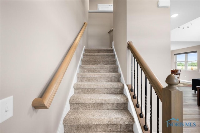 staircase featuring a towering ceiling and hardwood / wood-style flooring