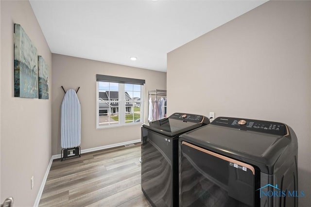 laundry area featuring washer and dryer and light hardwood / wood-style flooring