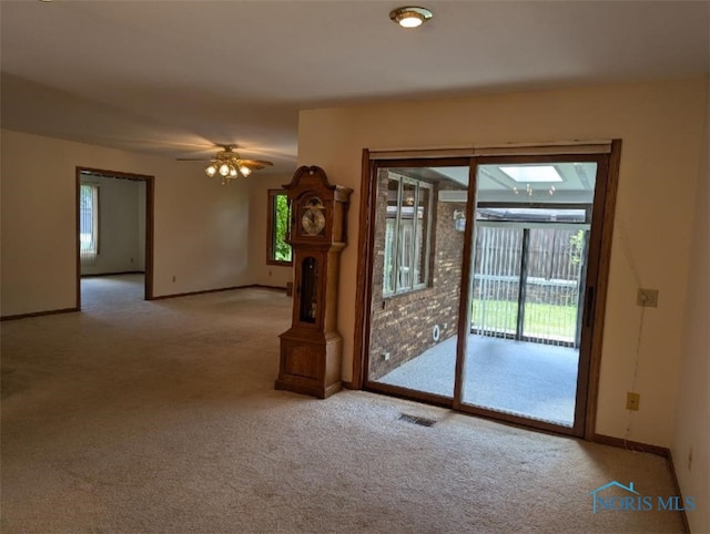 carpeted spare room featuring a skylight and ceiling fan