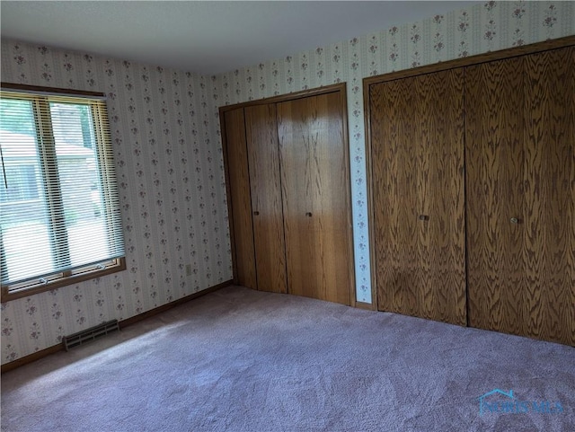 unfurnished bedroom with carpet and two closets