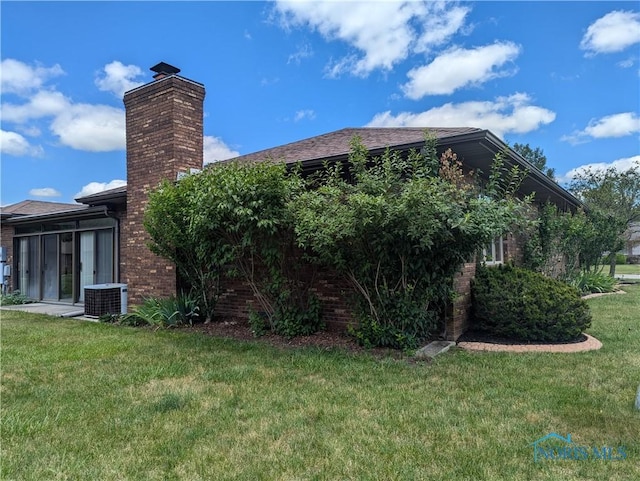 view of side of property featuring central AC, a lawn, and a sunroom