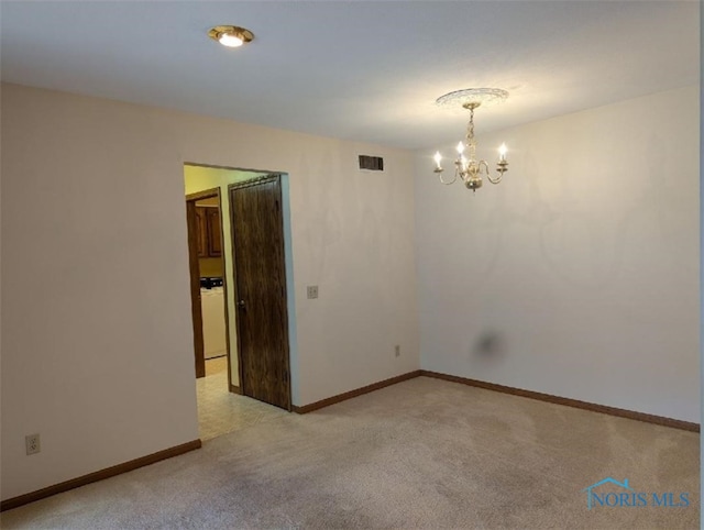 carpeted spare room featuring an inviting chandelier