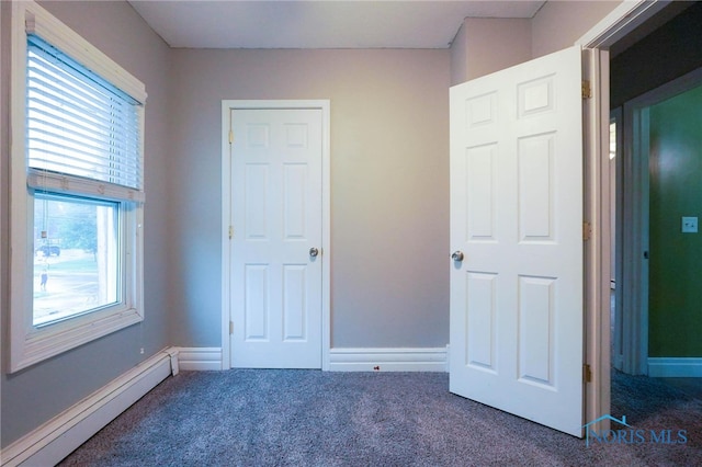 unfurnished bedroom with a baseboard radiator and dark colored carpet