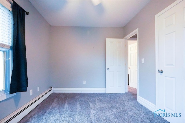 carpeted empty room with a baseboard heating unit