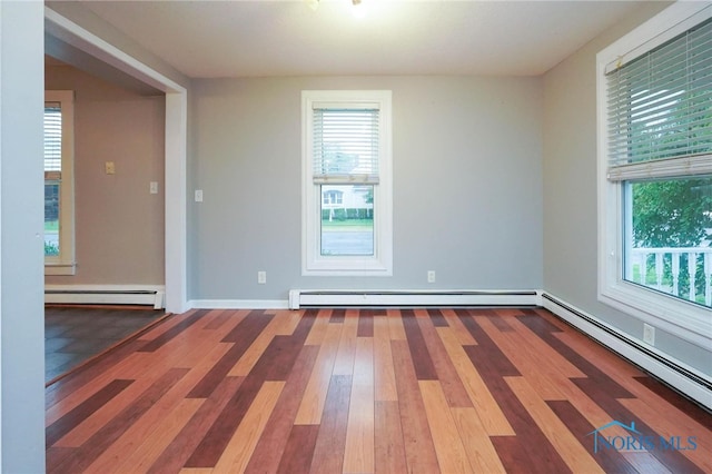 spare room with dark hardwood / wood-style flooring, a baseboard radiator, and a wealth of natural light