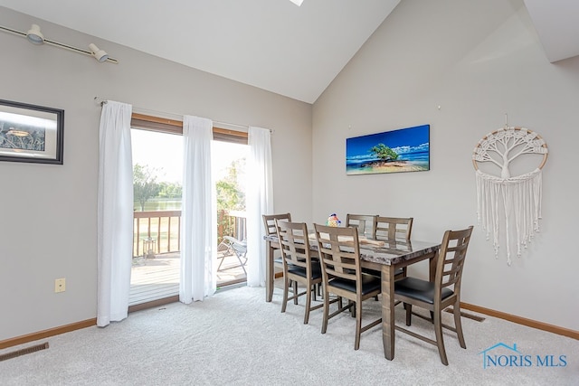 carpeted dining area featuring high vaulted ceiling