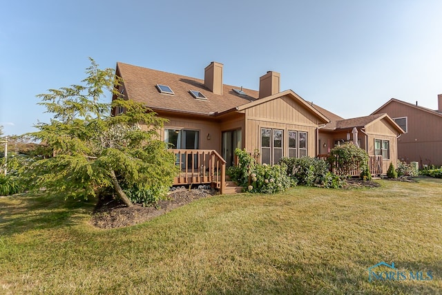 back of house with a wooden deck and a lawn