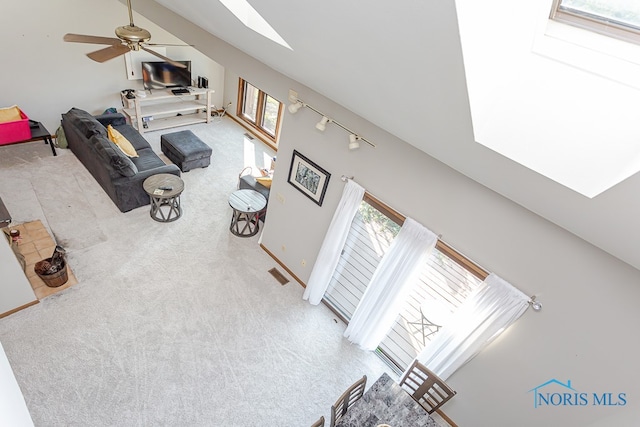 living room featuring ceiling fan, rail lighting, lofted ceiling with skylight, and carpet floors