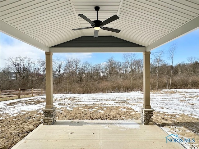 snow covered patio featuring a ceiling fan and fence