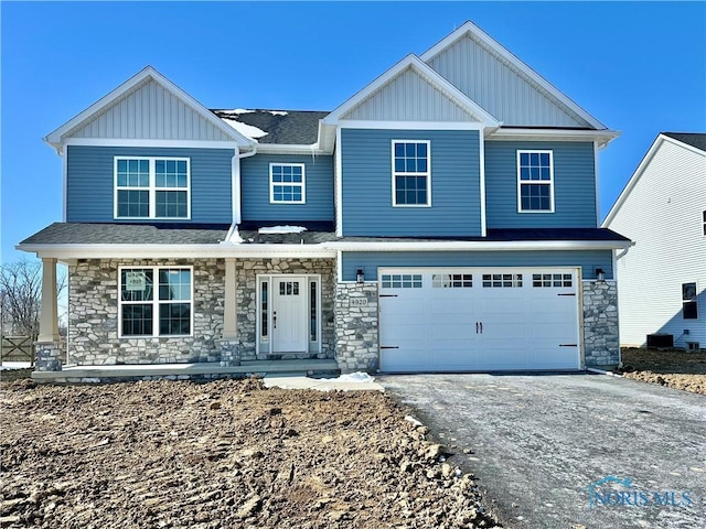 craftsman-style house with a porch, an attached garage, driveway, stone siding, and board and batten siding