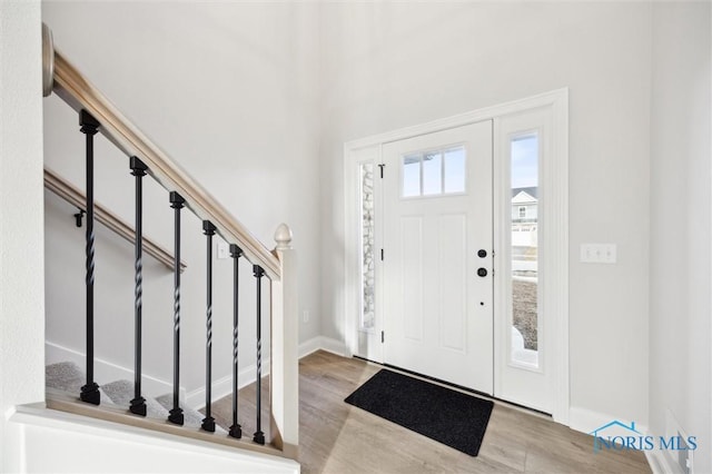 foyer with stairway, baseboards, and wood finished floors