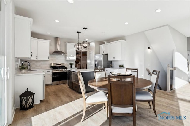 dining space with recessed lighting, light wood-type flooring, and an inviting chandelier