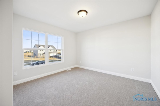 carpeted spare room featuring baseboards