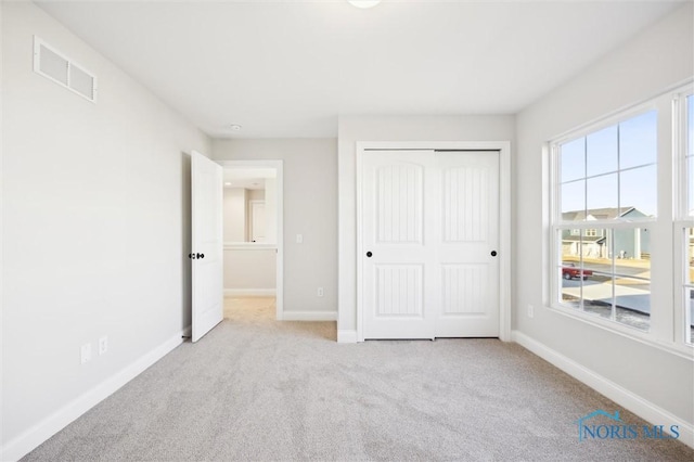 unfurnished bedroom featuring visible vents, multiple windows, carpet floors, and baseboards