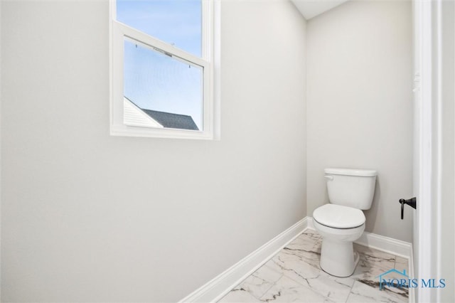 bathroom with baseboards, toilet, and marble finish floor