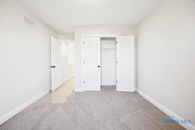 unfurnished bedroom featuring carpet flooring, baseboards, visible vents, and a closet