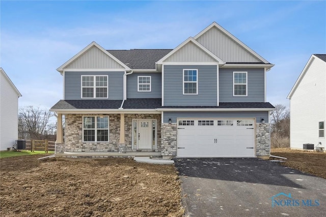 view of front of property with board and batten siding, cooling unit, driveway, stone siding, and an attached garage