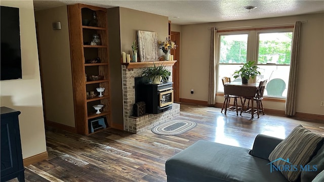 living room featuring a fireplace, a textured ceiling, and hardwood / wood-style flooring