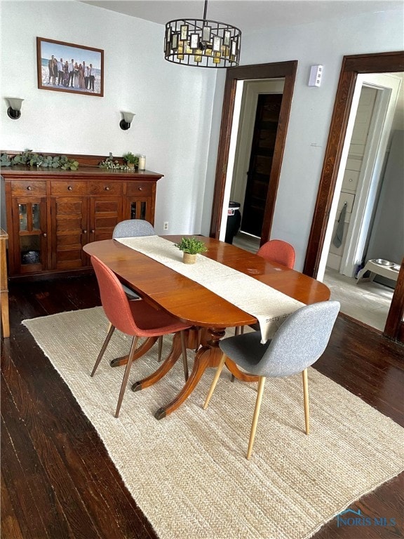 dining room with dark hardwood / wood-style flooring and a notable chandelier