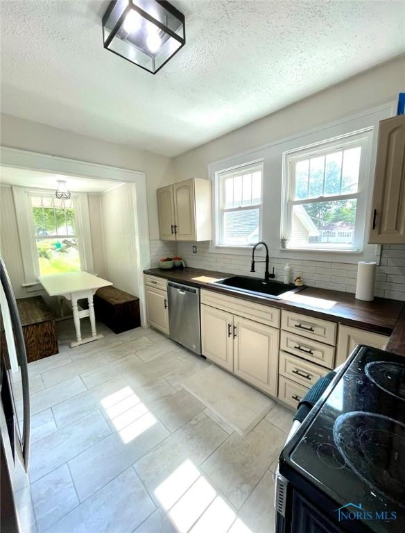 kitchen featuring plenty of natural light, dishwasher, backsplash, and light tile patterned floors