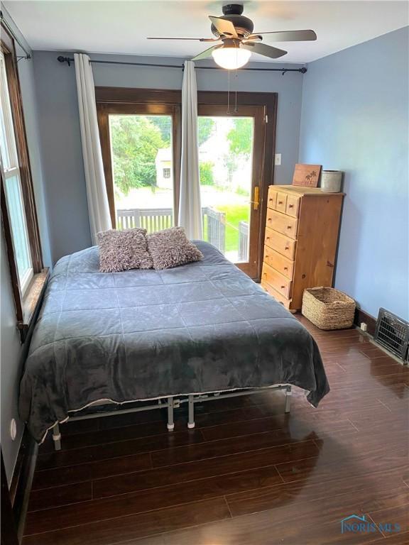 bedroom featuring access to exterior, multiple windows, ceiling fan, and wood-type flooring