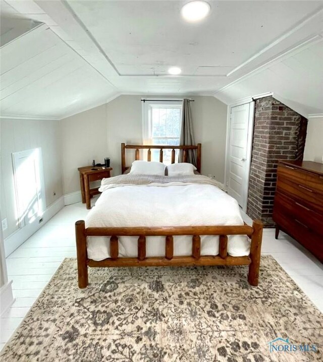 bedroom featuring hardwood / wood-style floors, brick wall, and vaulted ceiling