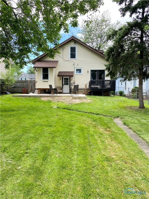 rear view of property featuring a wooden deck and a yard