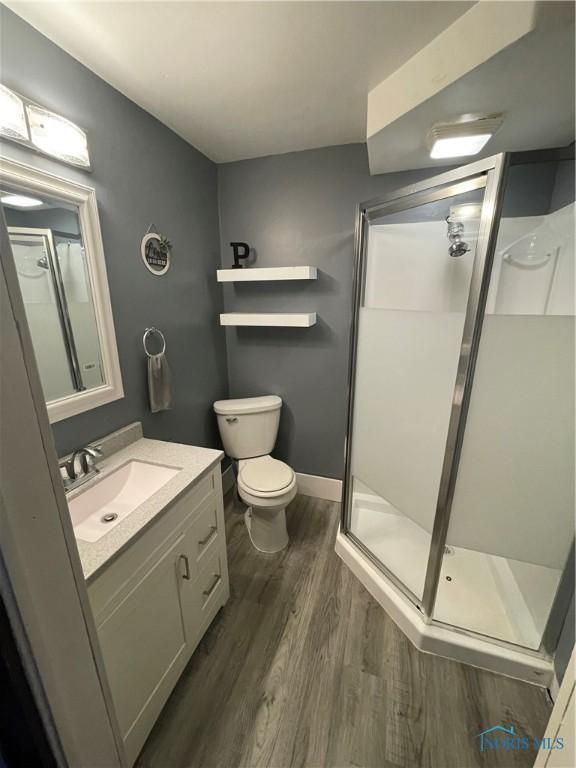 bathroom featuring a shower with shower door, vanity, toilet, and hardwood / wood-style floors