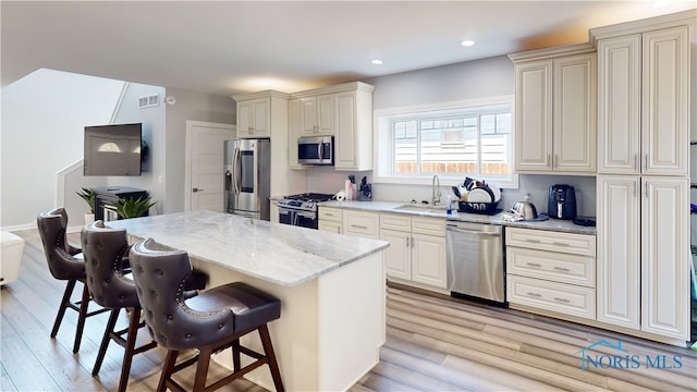 kitchen featuring sink, light stone countertops, light hardwood / wood-style flooring, and stainless steel appliances