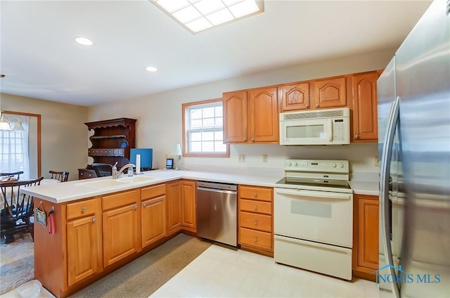 kitchen with sink, appliances with stainless steel finishes, light tile patterned floors, and kitchen peninsula