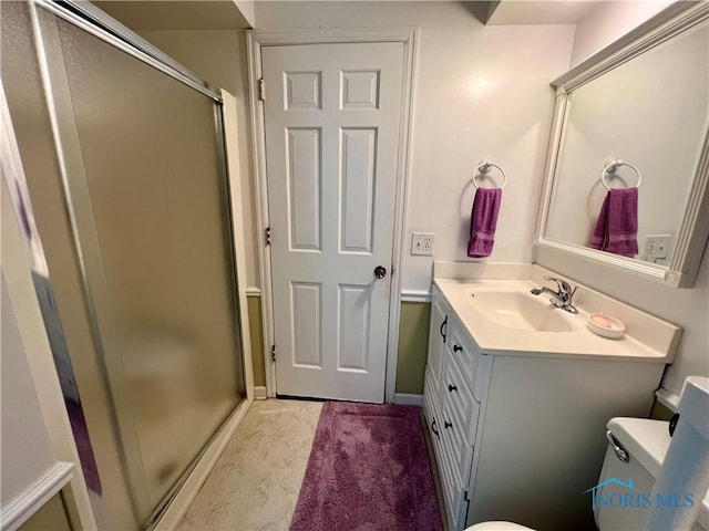 bathroom with vanity, toilet, and a shower with door