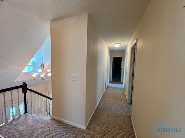 hallway with light colored carpet and a notable chandelier