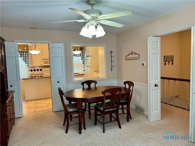 dining space with light carpet and ceiling fan