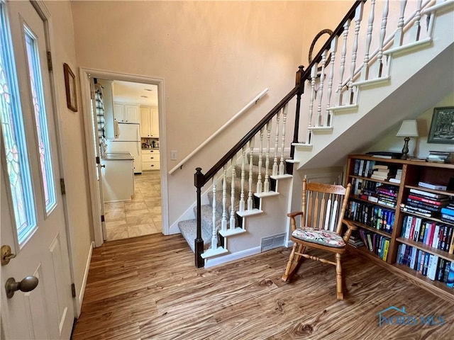 foyer entrance with hardwood / wood-style flooring and a towering ceiling