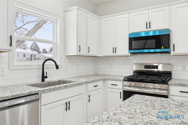 kitchen featuring white cabinetry, appliances with stainless steel finishes, sink, and backsplash