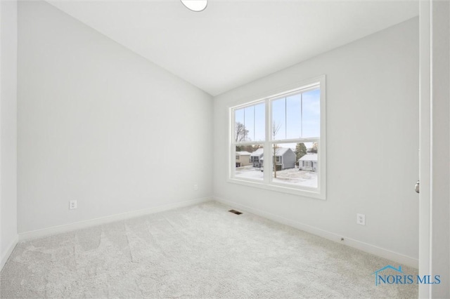 carpeted spare room featuring vaulted ceiling