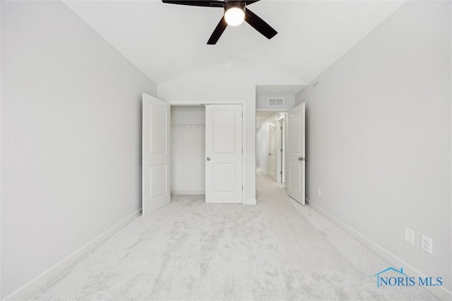 unfurnished bedroom with light carpet, ceiling fan, vaulted ceiling, and a closet