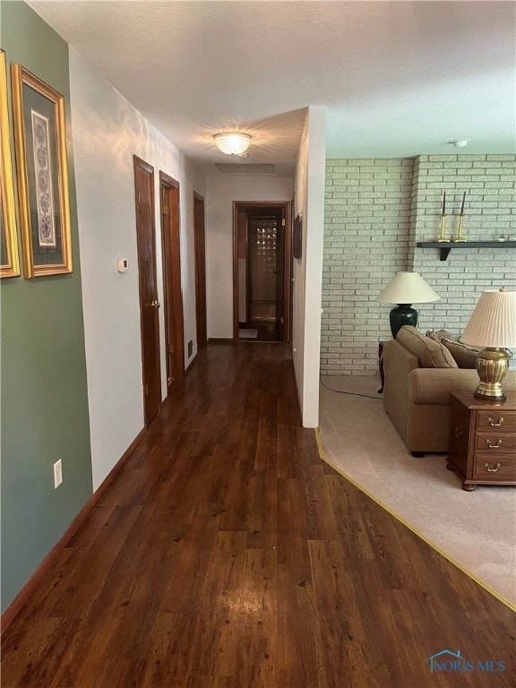 hall with dark hardwood / wood-style floors and brick wall