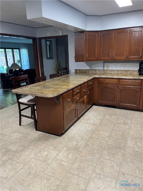 kitchen with decorative backsplash, kitchen peninsula, and a breakfast bar area