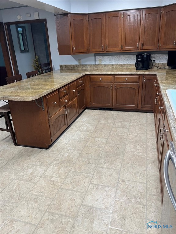 kitchen featuring a breakfast bar area, backsplash, and kitchen peninsula