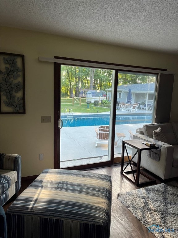 bedroom with hardwood / wood-style flooring, access to exterior, multiple windows, and a textured ceiling