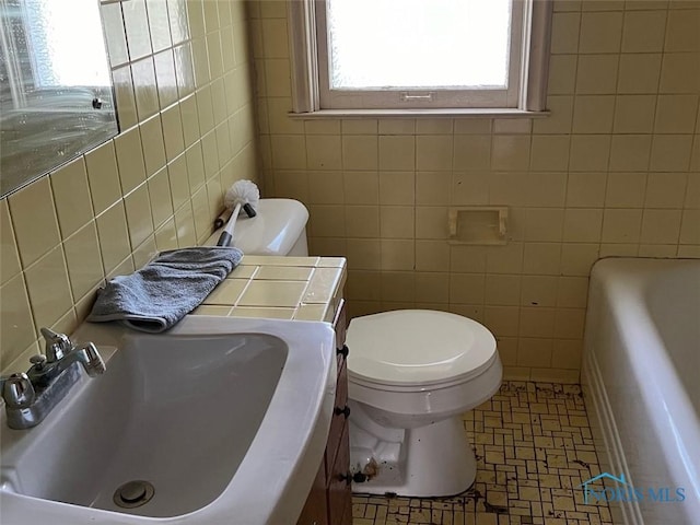 bathroom with toilet, sink, tile walls, and a tub